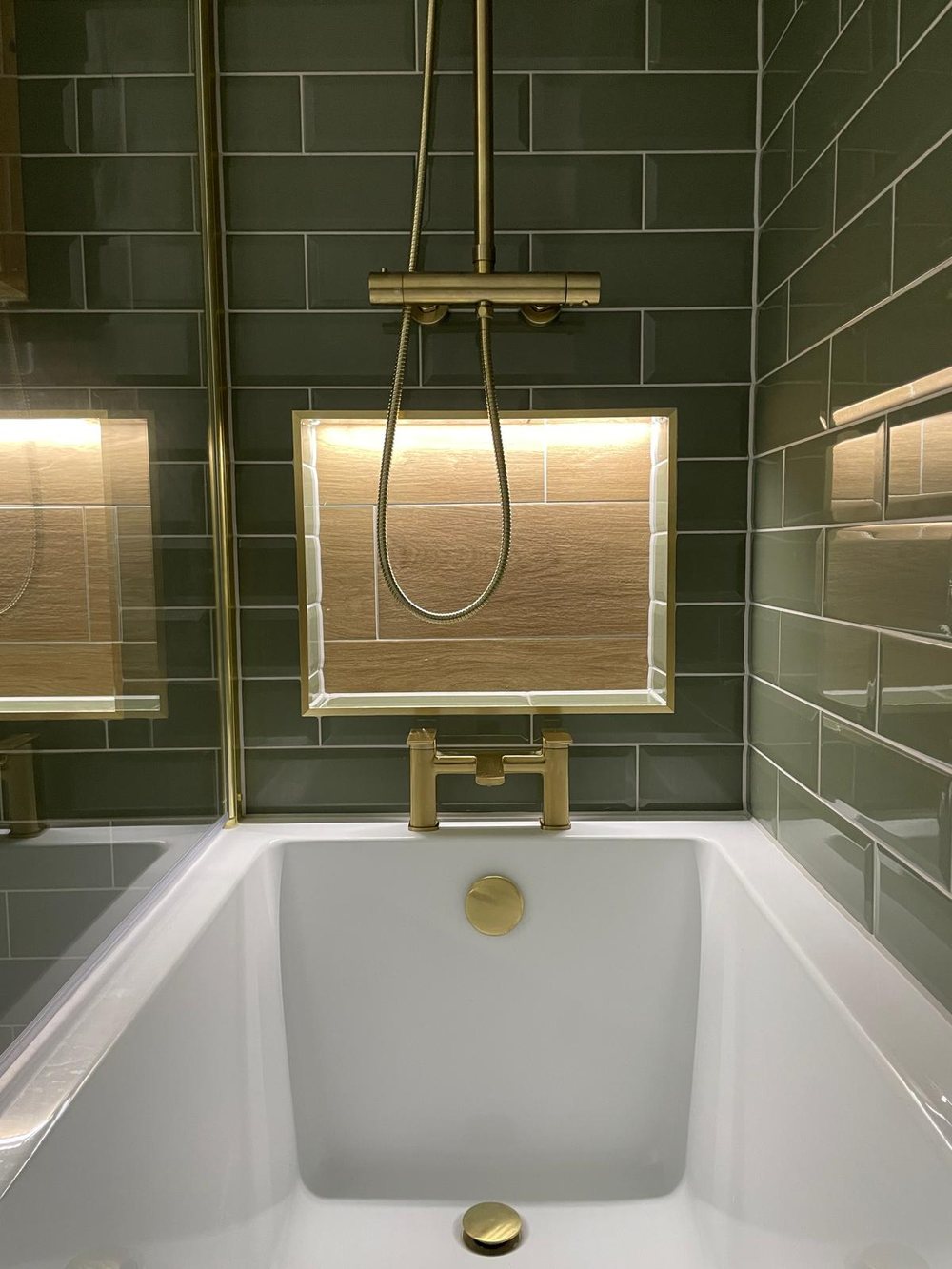 Green metro tiled shower with brass fittings