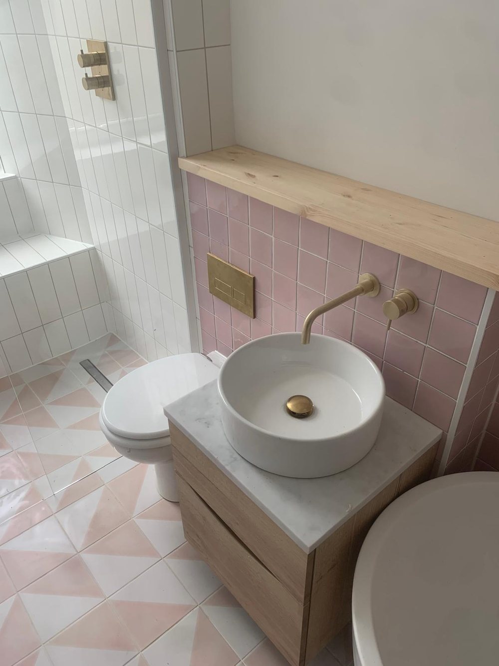 Pink tiled bathroom with a brass tap and stone basin